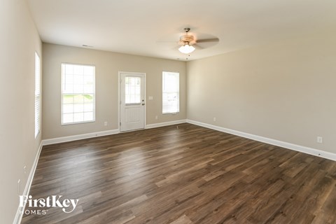 the spacious living room with hardwood flooring and a ceiling fan