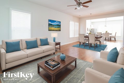A living room with a beige couch, a coffee table, and a painting on the wall.