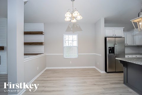 A kitchen with a refrigerator, cabinets, and a window.