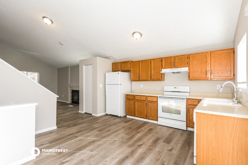 an empty kitchen with wooden cabinets and white appliances