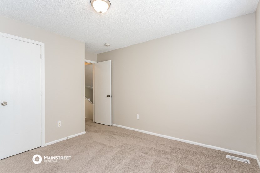 a spacious living room with carpet and a door to a closet