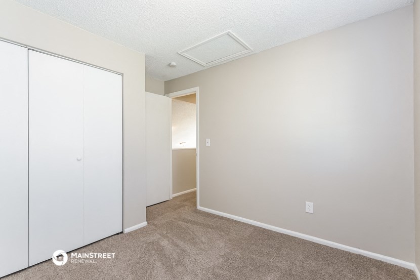 a bedroom with white walls and white closet doors