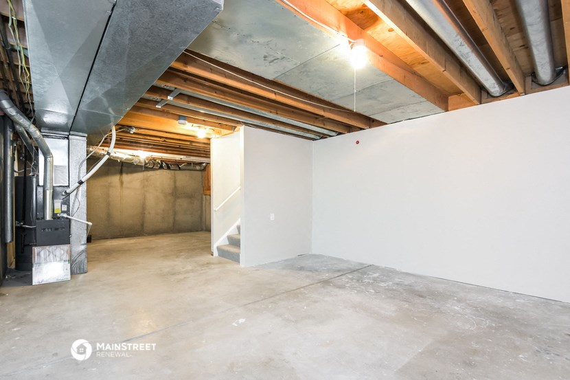 the basement of a building with white walls and exposed pipes