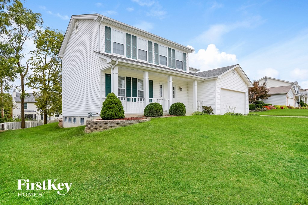 a white house with green shutters and a lawn