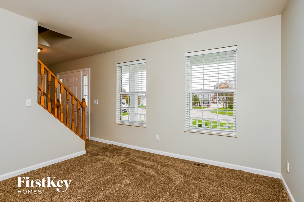 the living room and entryway of a house with carpeted floors