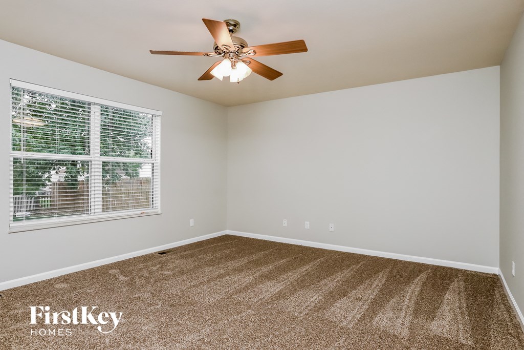 an empty room with a ceiling fan and a window