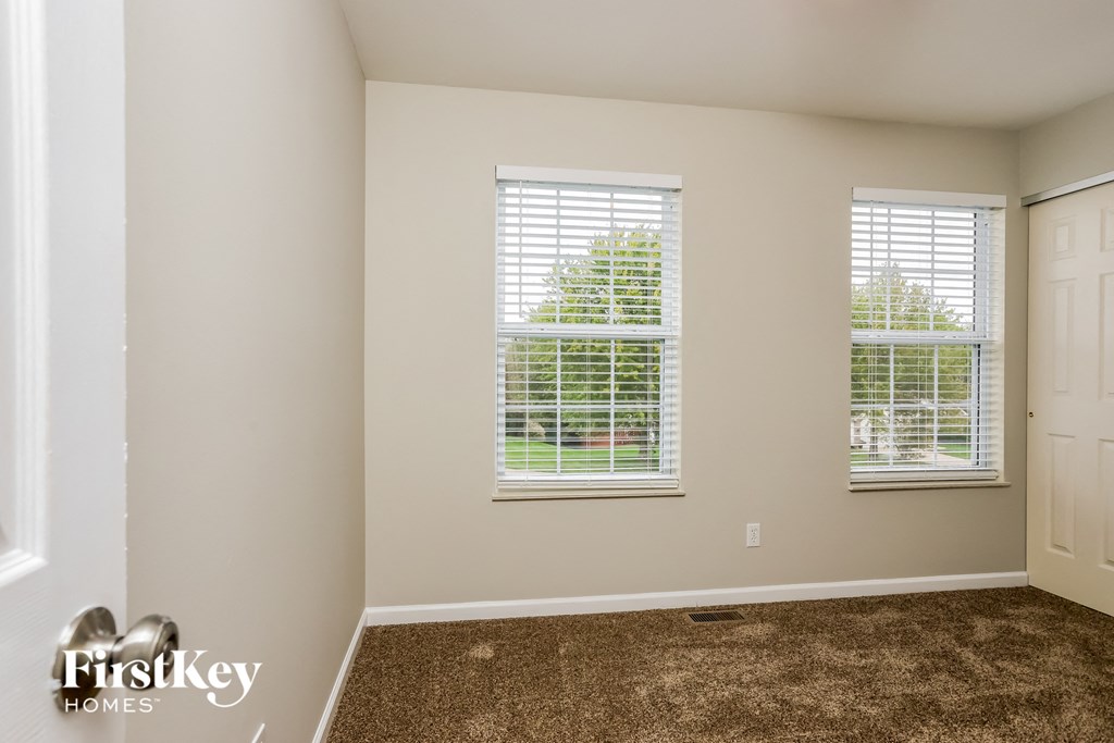 a bedroom with carpet and two windows and a door