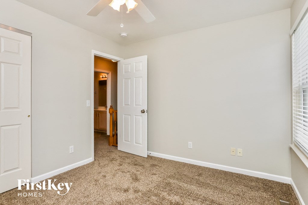 a bedroom with a carpeted floor and a door to a bathroom