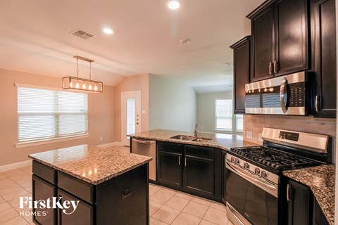 the kitchen has a large island with granite counter tops and black cabinets