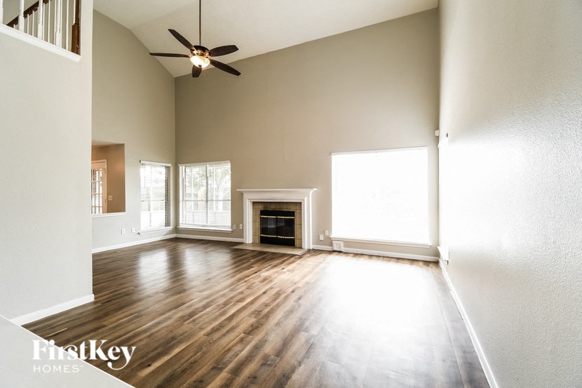 an empty living room with a ceiling fan and a fireplace