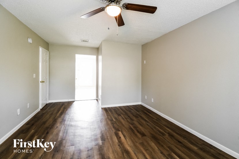 an empty living room with hardwood floors and a ceiling fan