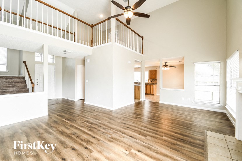 an empty living room with a ceiling fan and a staircase