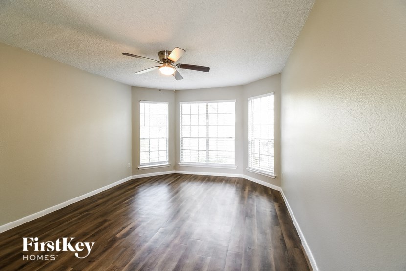 an empty living room with a ceiling fan and windows