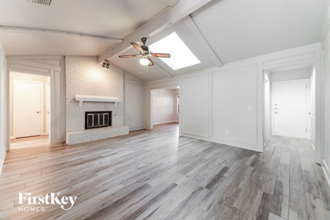 A spacious room with wooden flooring and a fireplace.