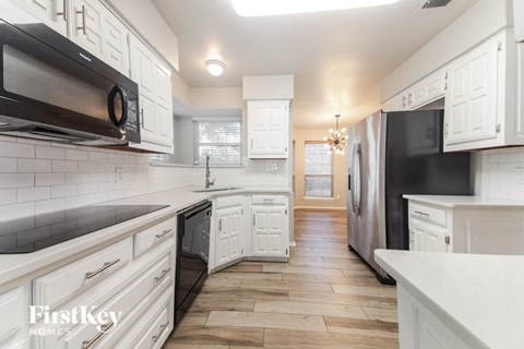 A kitchen with white cabinets and black appliances.