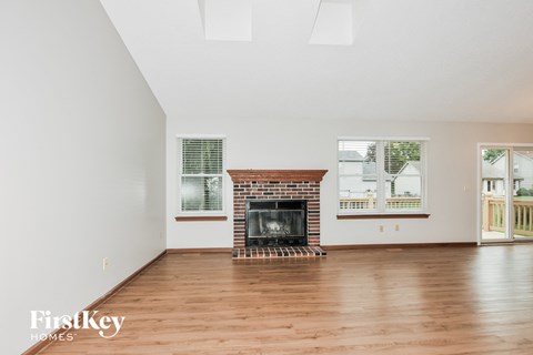 a living room with wood floors and a brick fireplace