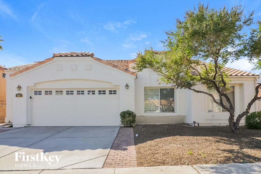a white house with a white garage door and a tree