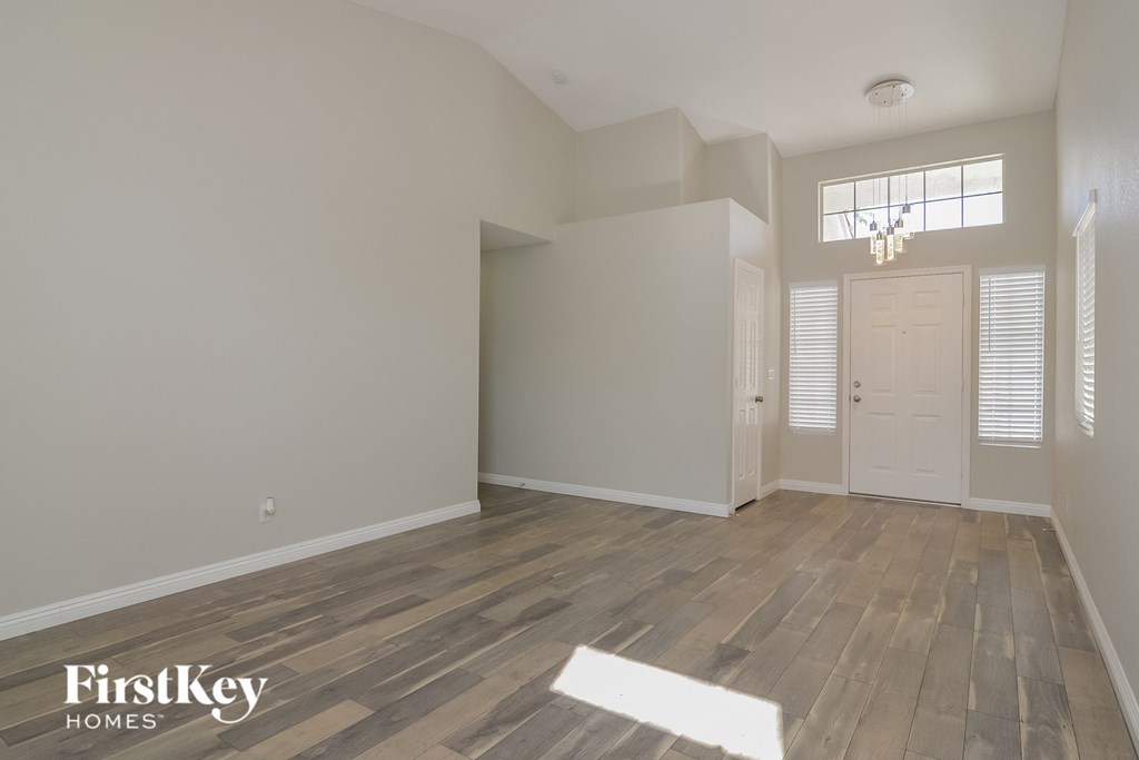the spacious living room with hardwood flooring and a white door