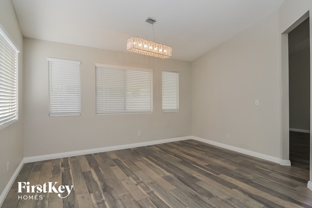 the living room of an empty house with wood floors and a chandelier