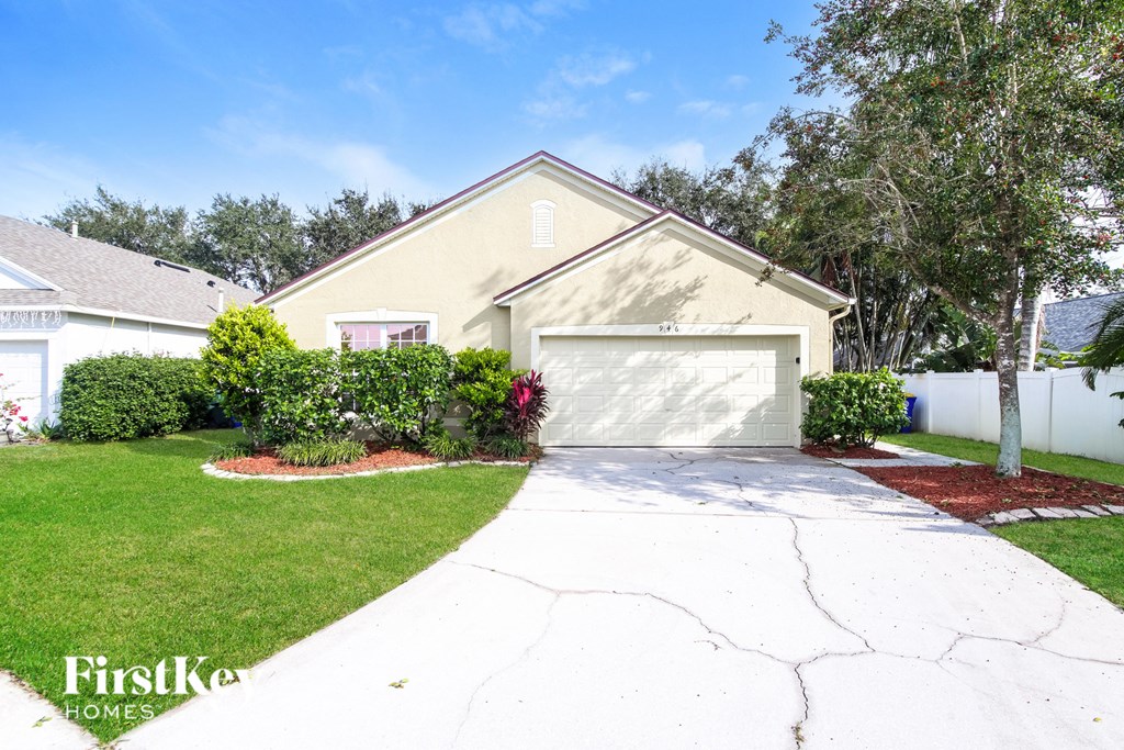a white driveway in front of a yellow house with a garage door
