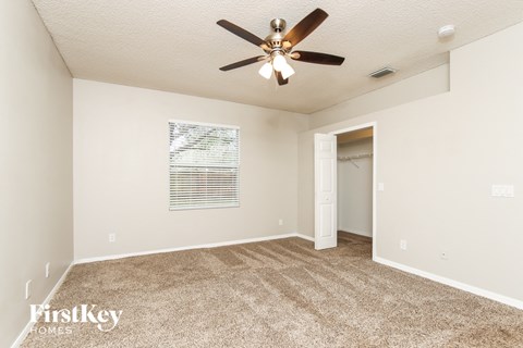 a spacious living room with carpet and a ceiling fan
