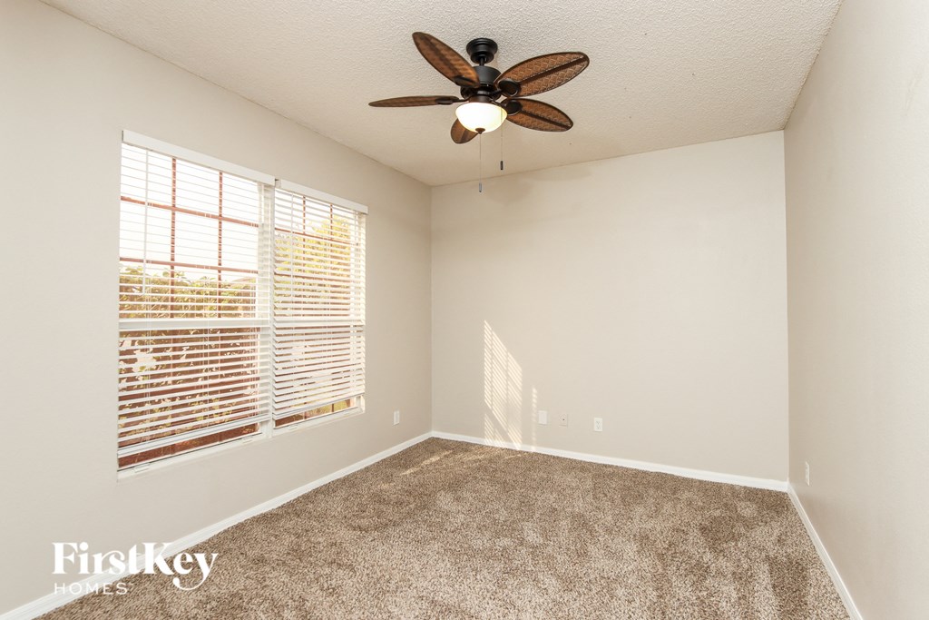 a bedroom with a ceiling fan and a large window