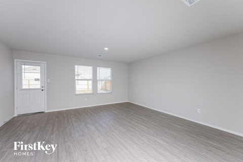 the living room of a home with white walls and wood floors