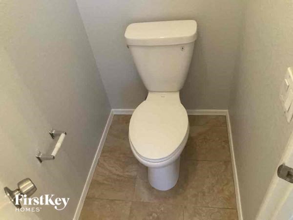 A white toilet in a small bathroom with a FirstKey Homes logo.