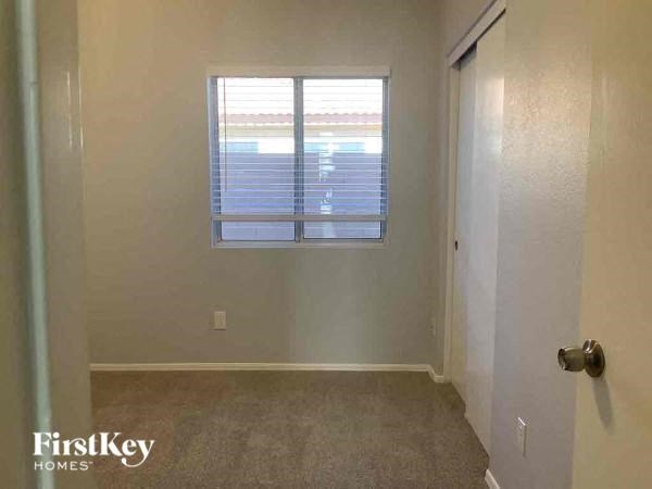 A room with a carpeted floor and a window with blinds.