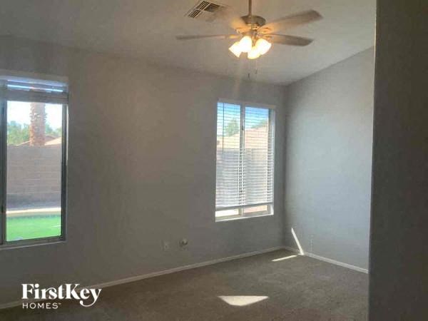 A room with a ceiling fan and a window with blinds.