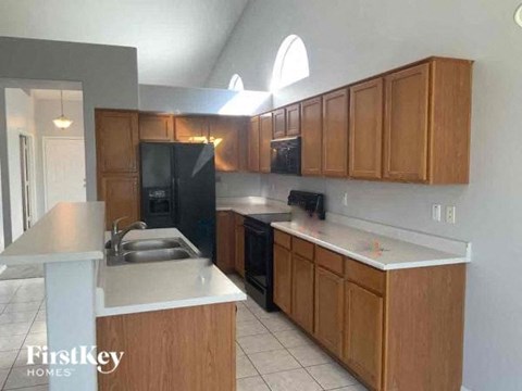 A kitchen with wooden cabinets and a black refrigerator.