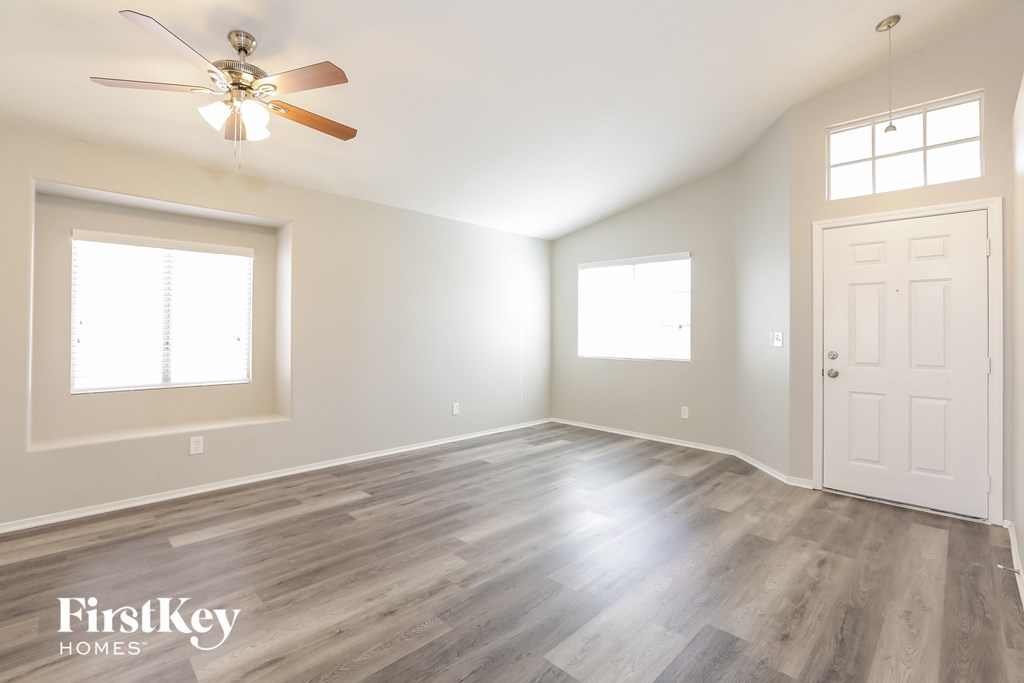 the living room of an empty house with a ceiling fan