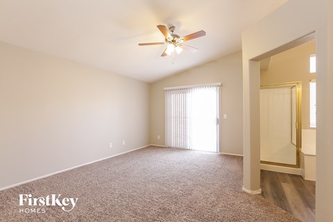 a spacious living room with carpet and a ceiling fan