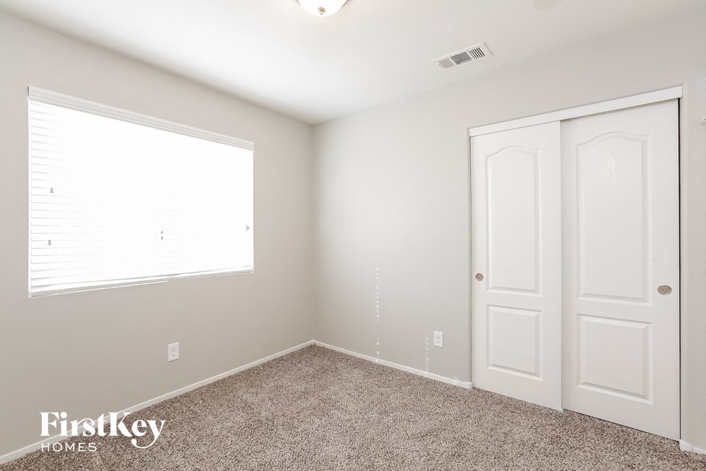 a bedroom with two closets and a window and carpet