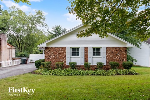 a white house with white shutters and a lawn and a tree
