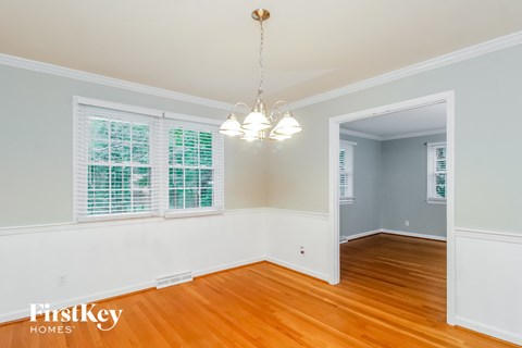 a living room with wood floors and white walls and a chandelier