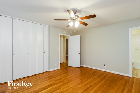 a bedroom with wood floors and a ceiling fan