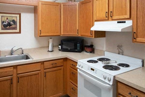 A kitchen with a white stove and wooden cabinets.