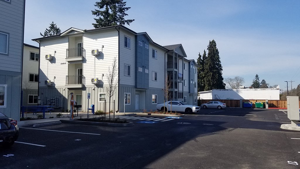 a row of apartment buildings with cars parked in a parking lot
