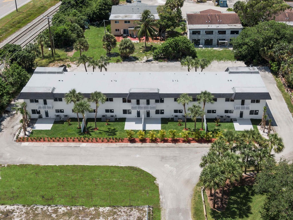 an aerial view of a building with palm trees in front of it