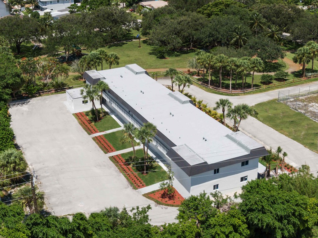 an aerial view of a building with a parking lot and trees