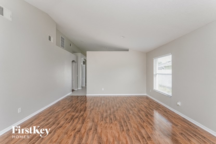 A room with wooden flooring and a window with blinds.
