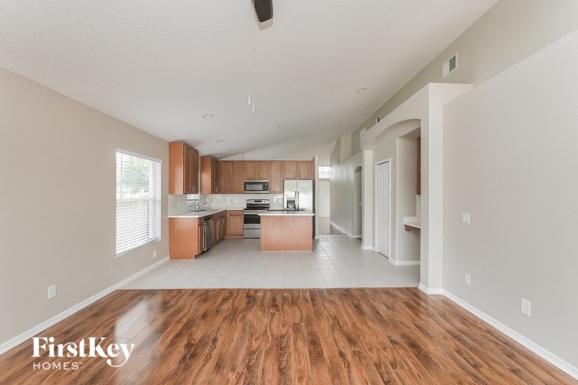 A spacious kitchen with wooden floors and a ceiling fan.