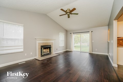 an empty living room with a fireplace and a ceiling fan