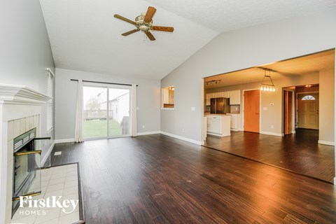 an empty living room with a fireplace and a ceiling fan