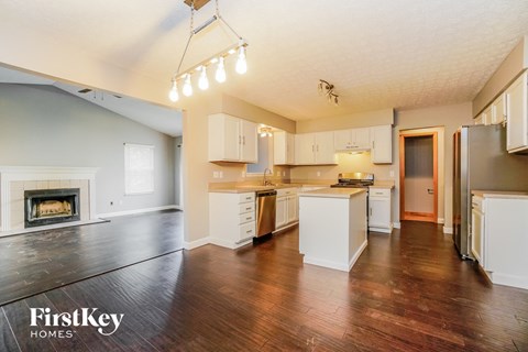 a kitchen with white cabinets and a fireplace and a wood floor