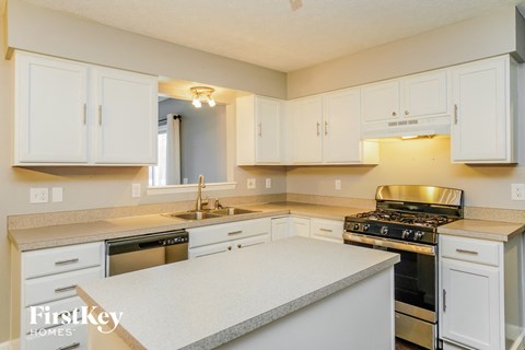 a kitchen with white cabinets and a stove and a sink