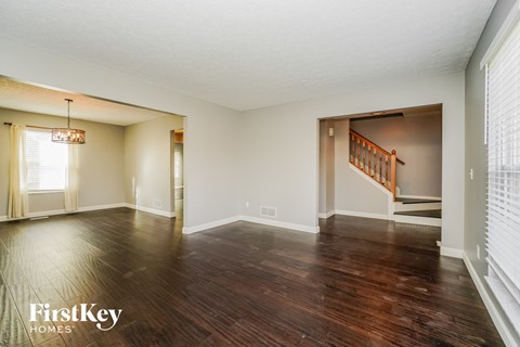 an empty living room with hard wood floors and a staircase
