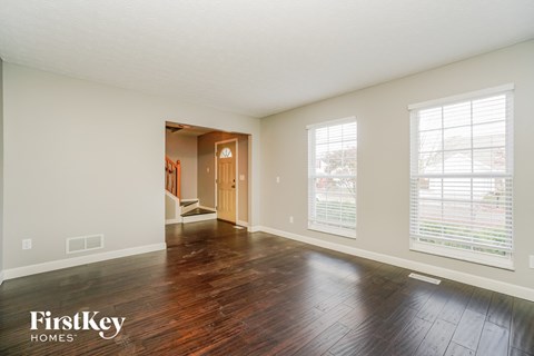 an empty living room with hard wood floors and white walls