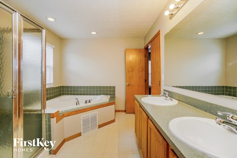 a bathroom with two sinks and a tub and a shower